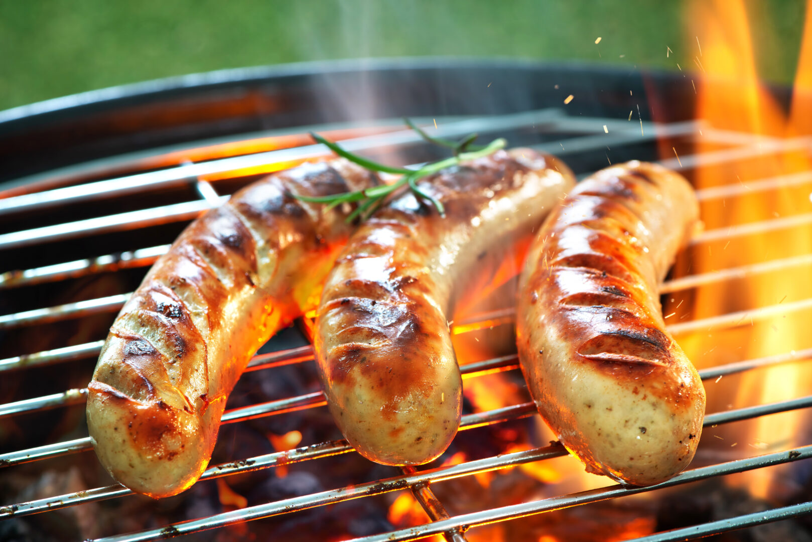 Delicious sausages sizzling over the coals on barbecue grill