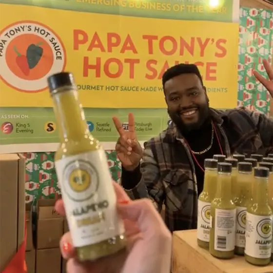 Vendor selling hot sauce at Christmas market.