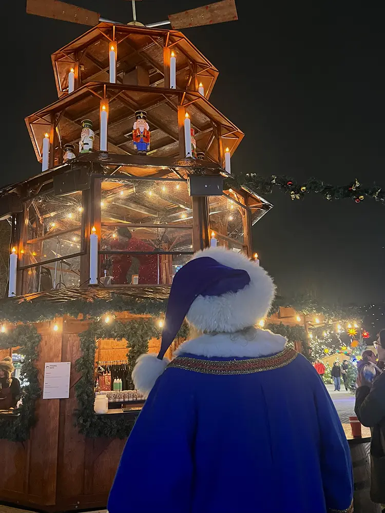 Santa wearing a blue costume looking at a tall pyramid.