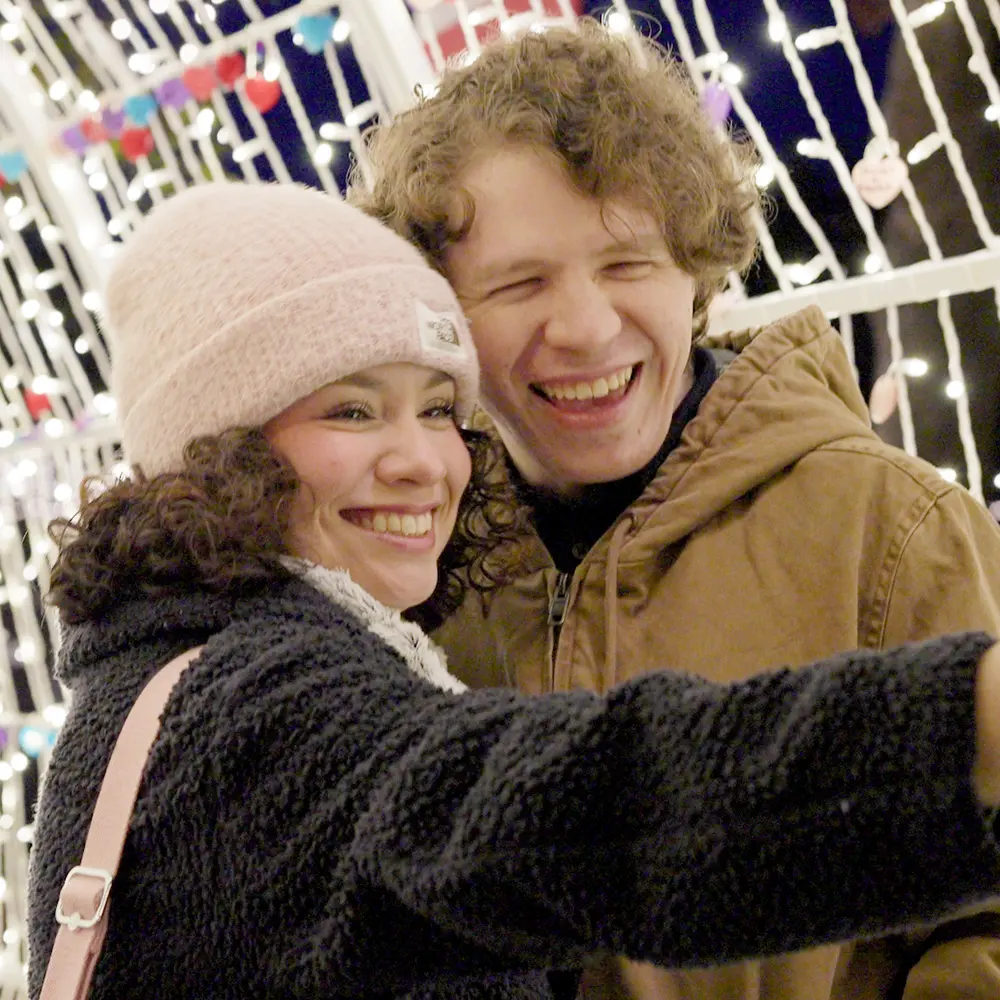 People taking a selfie inside a tunnel with Christmas lights.