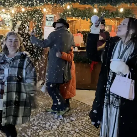 Girl walking in snow shower at Christmas market.